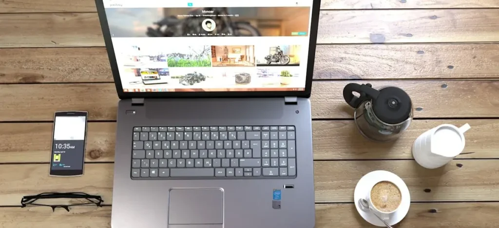 Vue de dessus d’un ordinateur affichant un site web avec smartphone et café, illustrant une demande de devis pour un site vitrine sur mesure