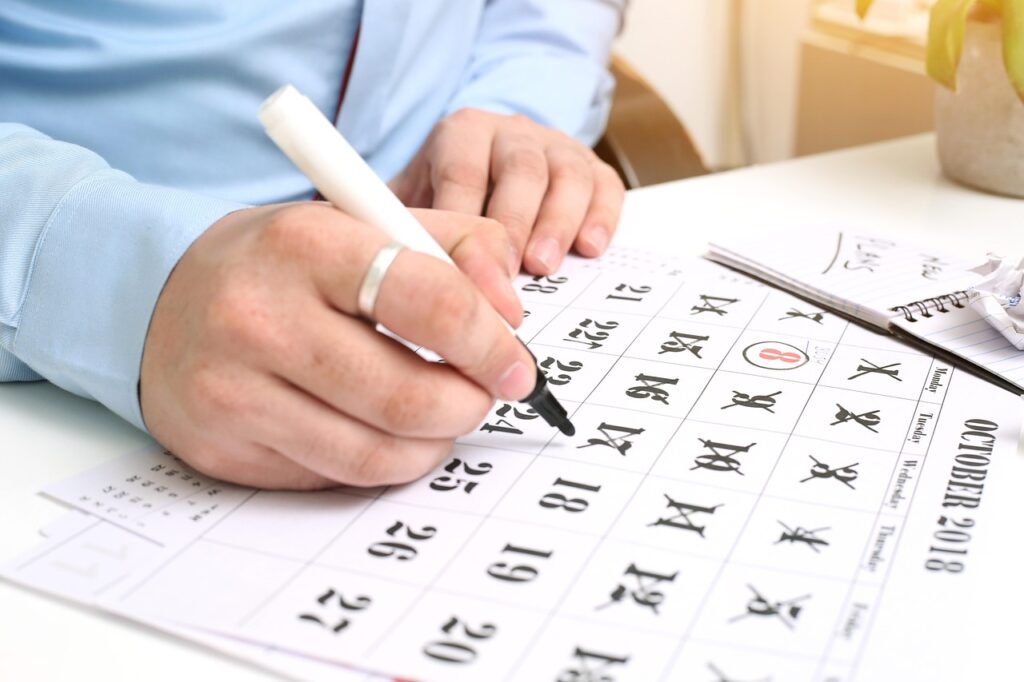 Main écrivant sur un calendrier interactif personnalisé