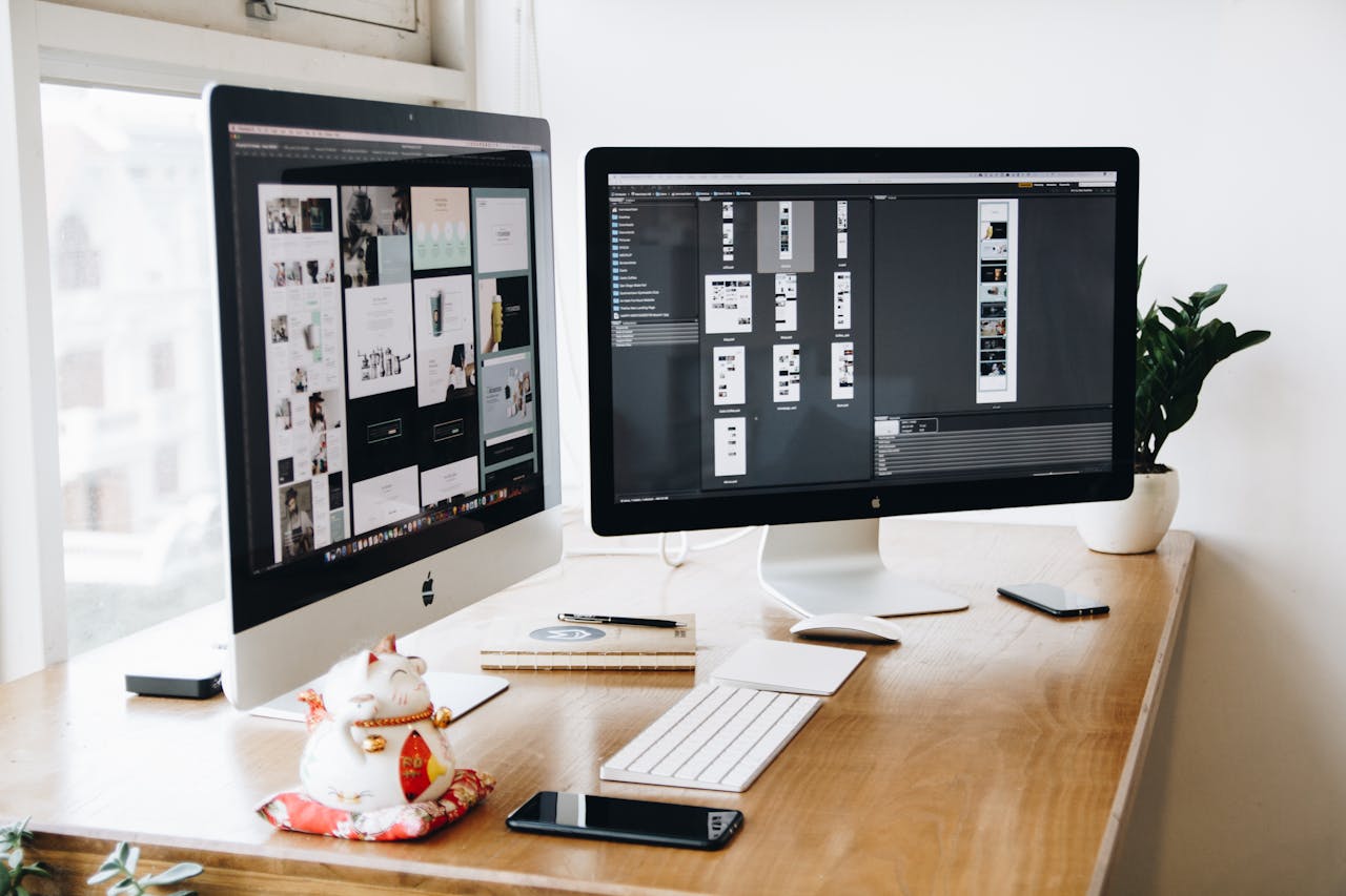 Bureau avec deux écrans affichant des maquettes de design pour solutions d’entreprise